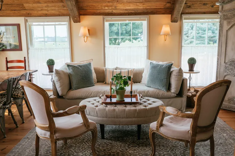 The salon at Le Mas de Grâce — deep sofas and tall shuttered windows on a stone floor.